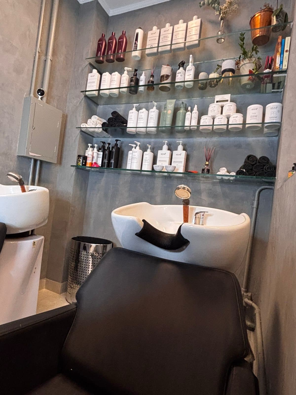 Prateleira com produtos Keune ao lado dos lavatórios